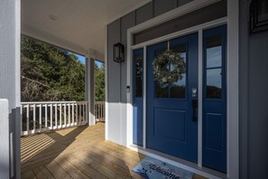 A wooden deck with a blue door, a white railing, and a welcome mat. - Bubbles Up: Private Pool, Hot Tub, Currituck Club Resort (Corolla)