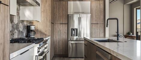 Una cocina moderna con estufa a gas, refrigerador de acero inoxidable y armarios de madera.