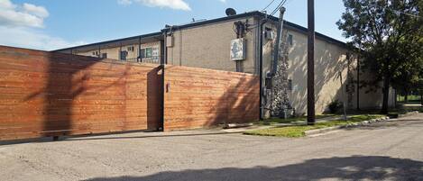 A building with a brick exterior, a wooden gate, and a satellite dish on the roof.