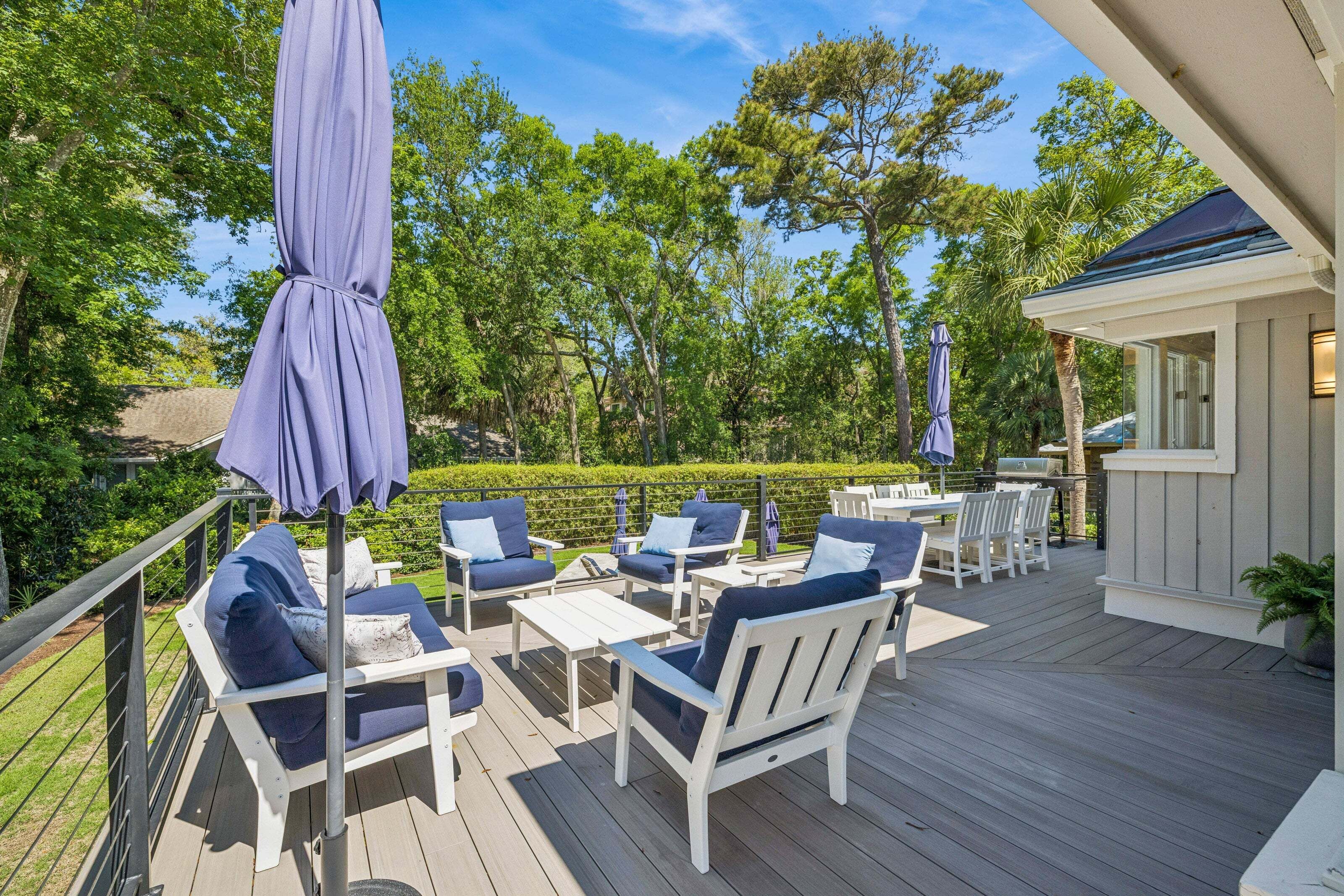 A deck with outdoor furniture, a barbecue area, and a view of the surrounding greenery.