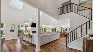 Un vaste espace de vie comprenant un grand canapé, une table à manger et un escalier.