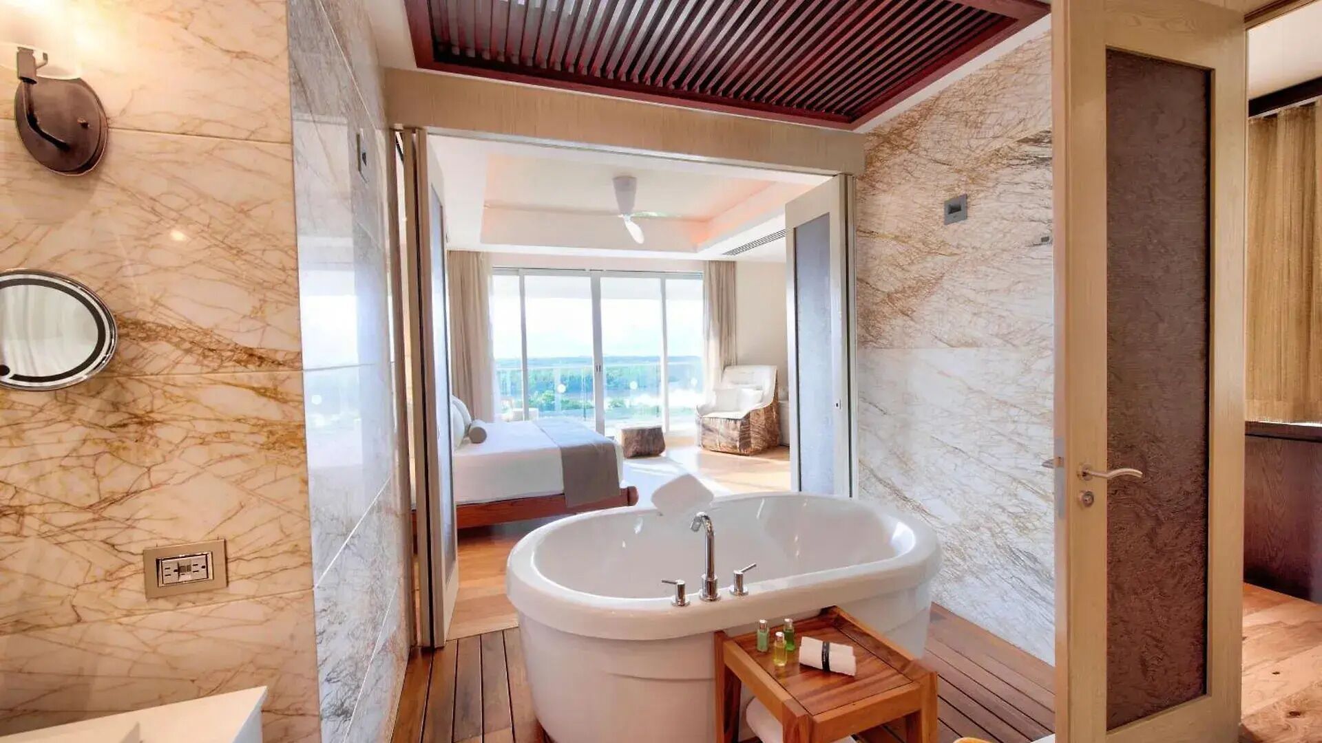 Un baño moderno con una bañera grande, piso de madera y pared de mármol.
