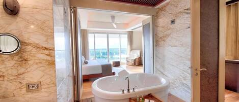 Un baño moderno con una bañera grande, piso de madera y pared de mármol.