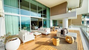 A spacious outdoor lounge area with a wooden deck, white sofas, and a large potted plant. - 2 Bedroom Loft Vidanta World & VIP Park Golf 2x1 Access (Nuevo Vallarta)