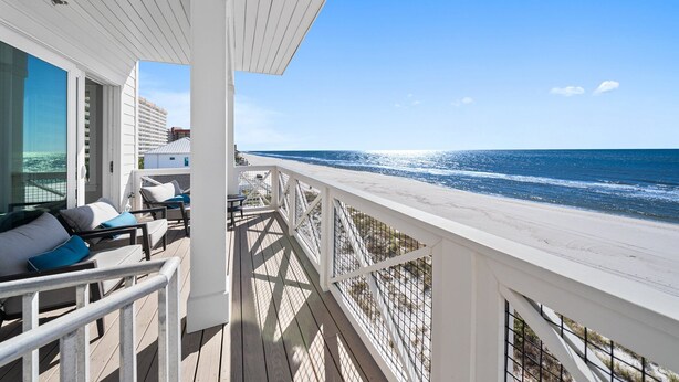 Ein Balkon am Strand mit Blick aufs Meer, ausgestattet mit Stühlen und einem Tisch.