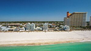 Ein Küstenhotel mit Zimmern direkt am Strand, ein großes Gebäude mit einem Turm und ein Sandstrand.