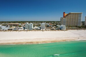 A coastal hotel with beachfront rooms, a large building with a tower, and a sandy beach.