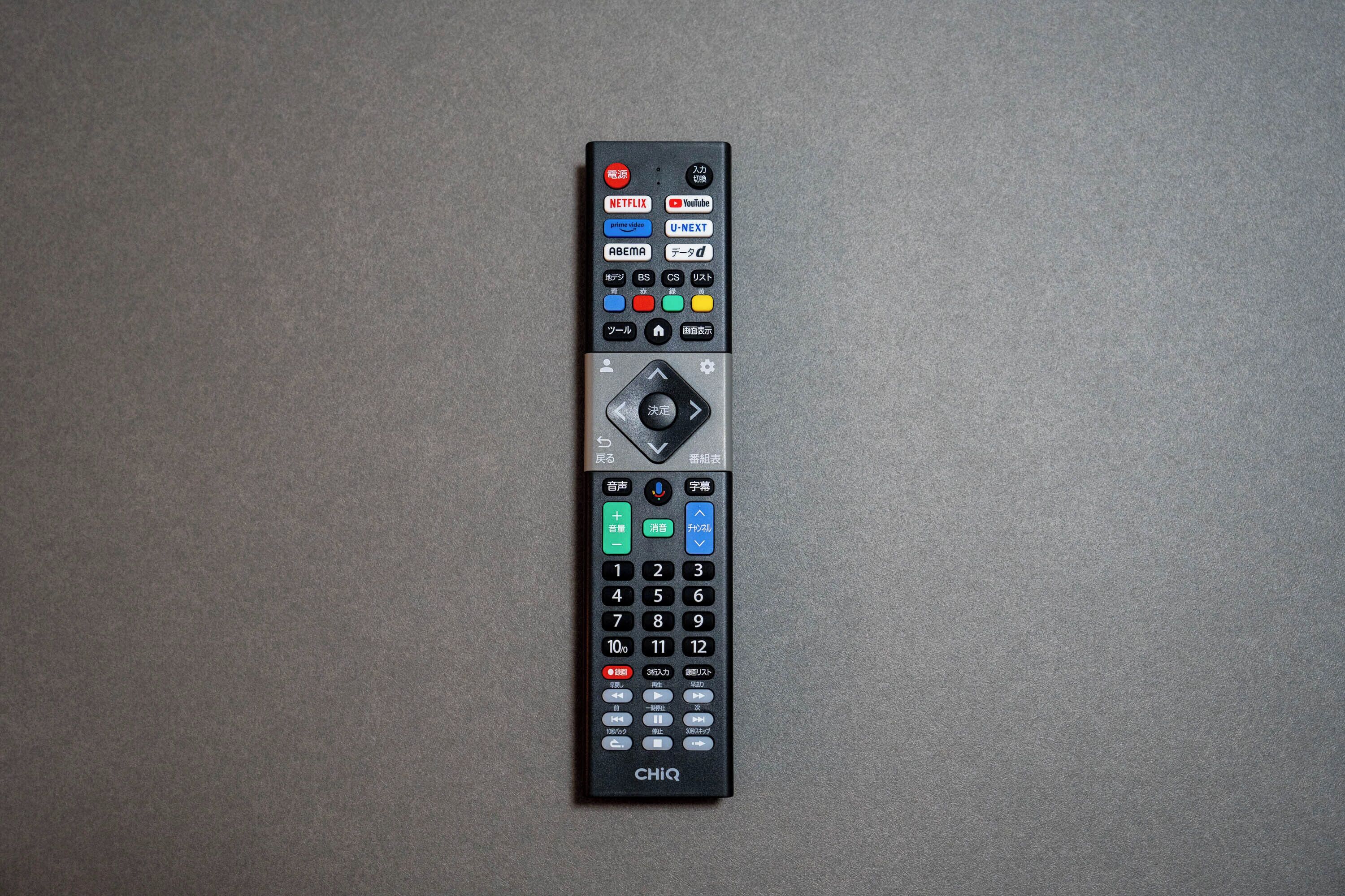 A black remote control with multiple buttons and a numeric keypad.