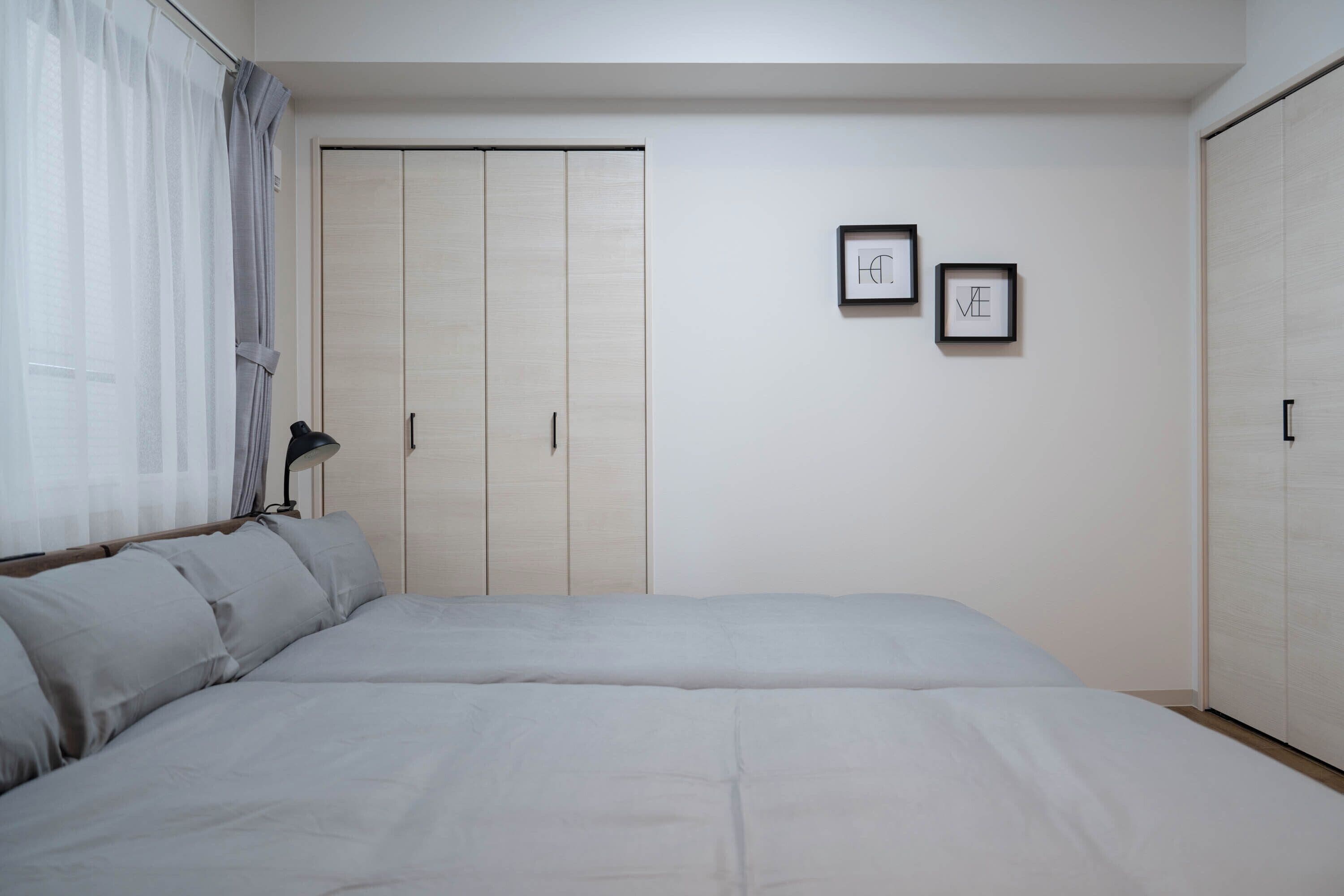 Ein Schlafzimmer mit einem großen Bett, einem Kleiderschrank und zwei gerahmten Bildern an der Wand.