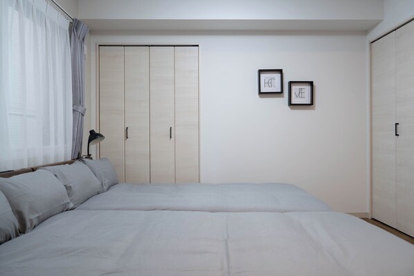 Un dormitorio con una cama grande, un armario y dos cuadros en la pared.