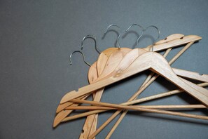 Perchas de madera con ganchos metálicos sobre un fondo gris.