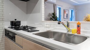 A modern kitchen with a stainless steel sink, a gas stove, and a white countertop. - ZABO HILLS 301 (Sapporo)