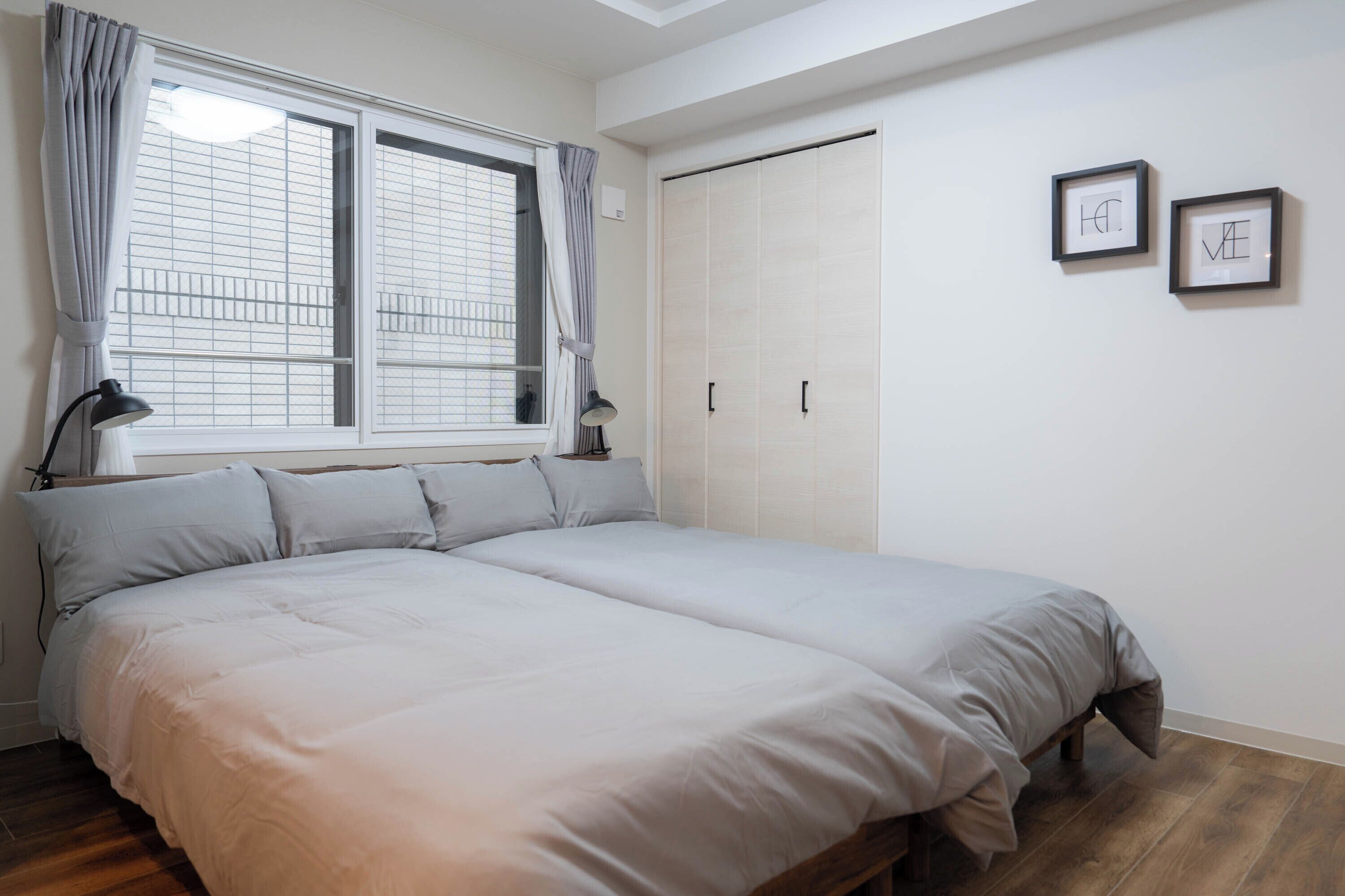 A bedroom with a large bed, a wardrobe, and two framed pictures on the wall.