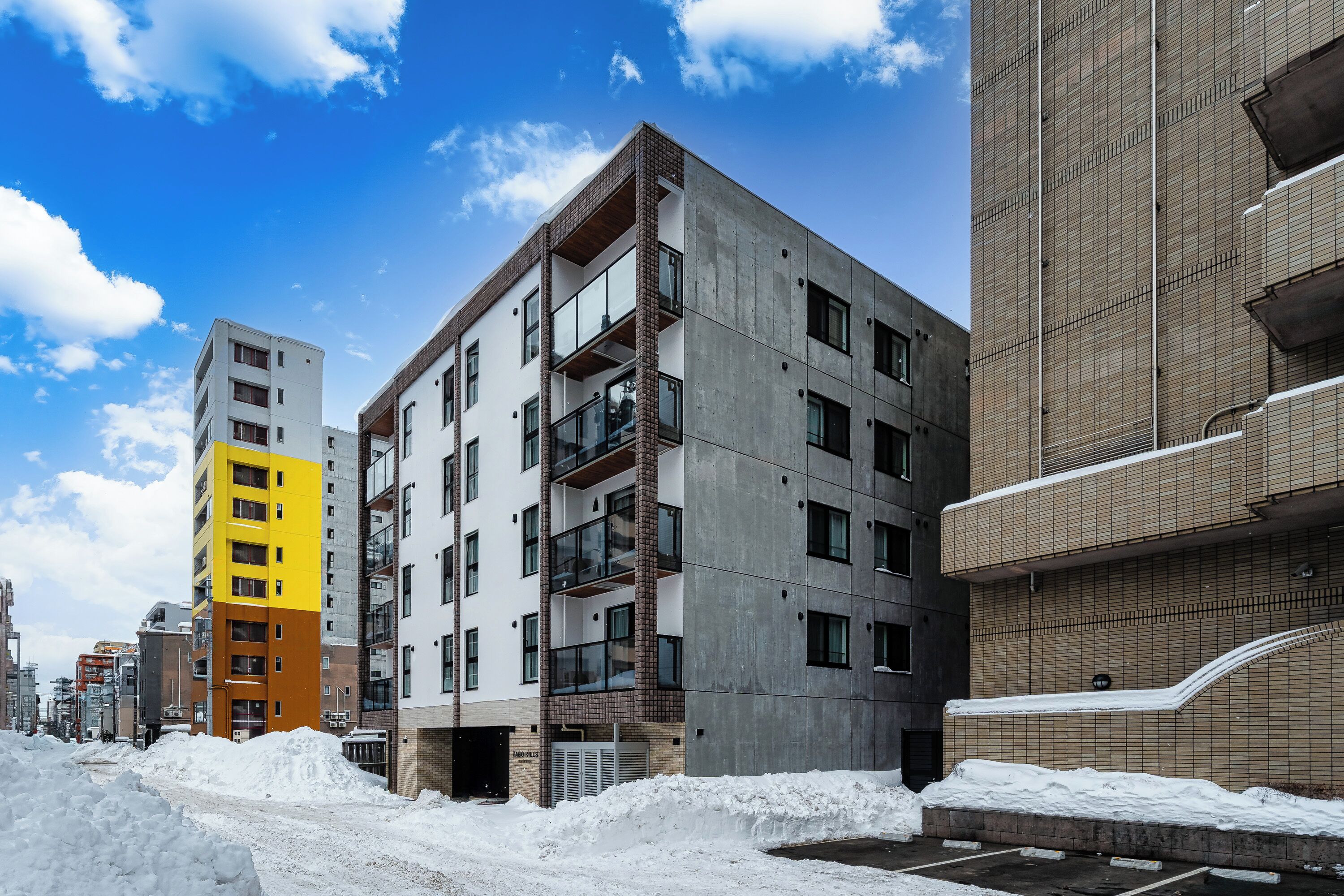 A multi-story building with balconies and large windows, surrounded by snow.