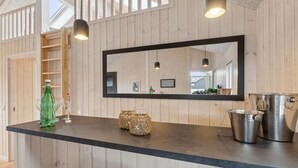 Une cuisine avec des murs en bois, un plan de travail noir, un grand miroir et des appareils électroménagers en acier inoxydable.