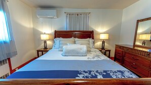 A neatly made bed with a blue and white bedspread, two bedside lamps, a wooden dresser, and a large mirror. - Family Stays: Middletown, CT (Middletown)