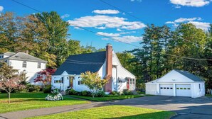 A residential house with a garage, surrounded by trees and a clear sky. - Family Stays: Middletown, CT (Middletown)