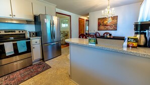 A modern kitchen with stainless steel appliances, a granite countertop, and a chandelier. - Family Stays: Middletown, CT (Middletown)
