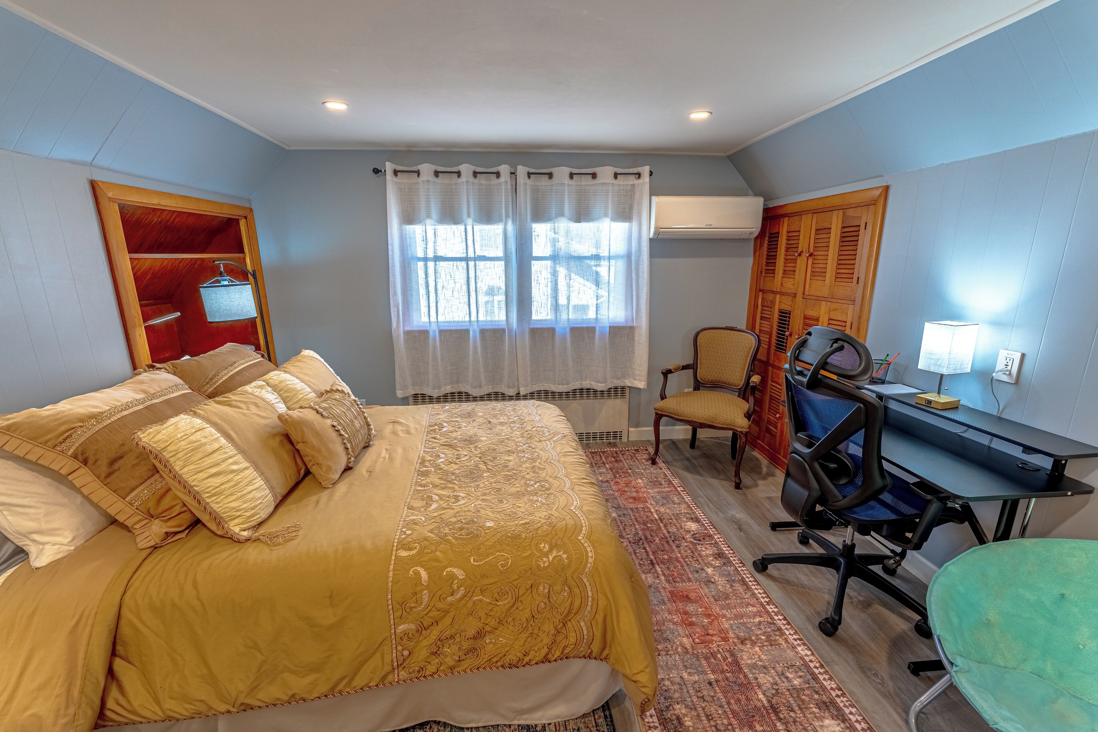 A bedroom with a bed, a desk, a chair, and a wardrobe.