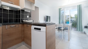 Una cocina moderna con armarios de madera, lavavajillas y un comedor con sillas y una mesa.