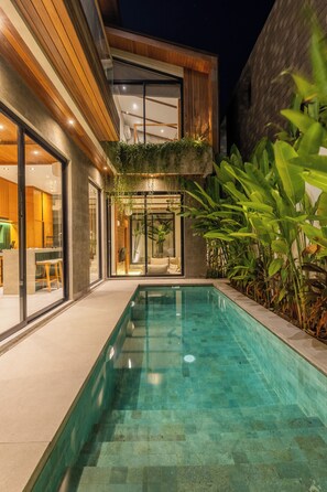 Una casa moderna con piscina, ventanas amplias y zona de comedor.
