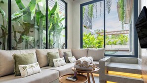 A modern living room with a sofa, a coffee table, and a staircase. - Nanna Villa Unit 2 by Betterplace (Canggu)