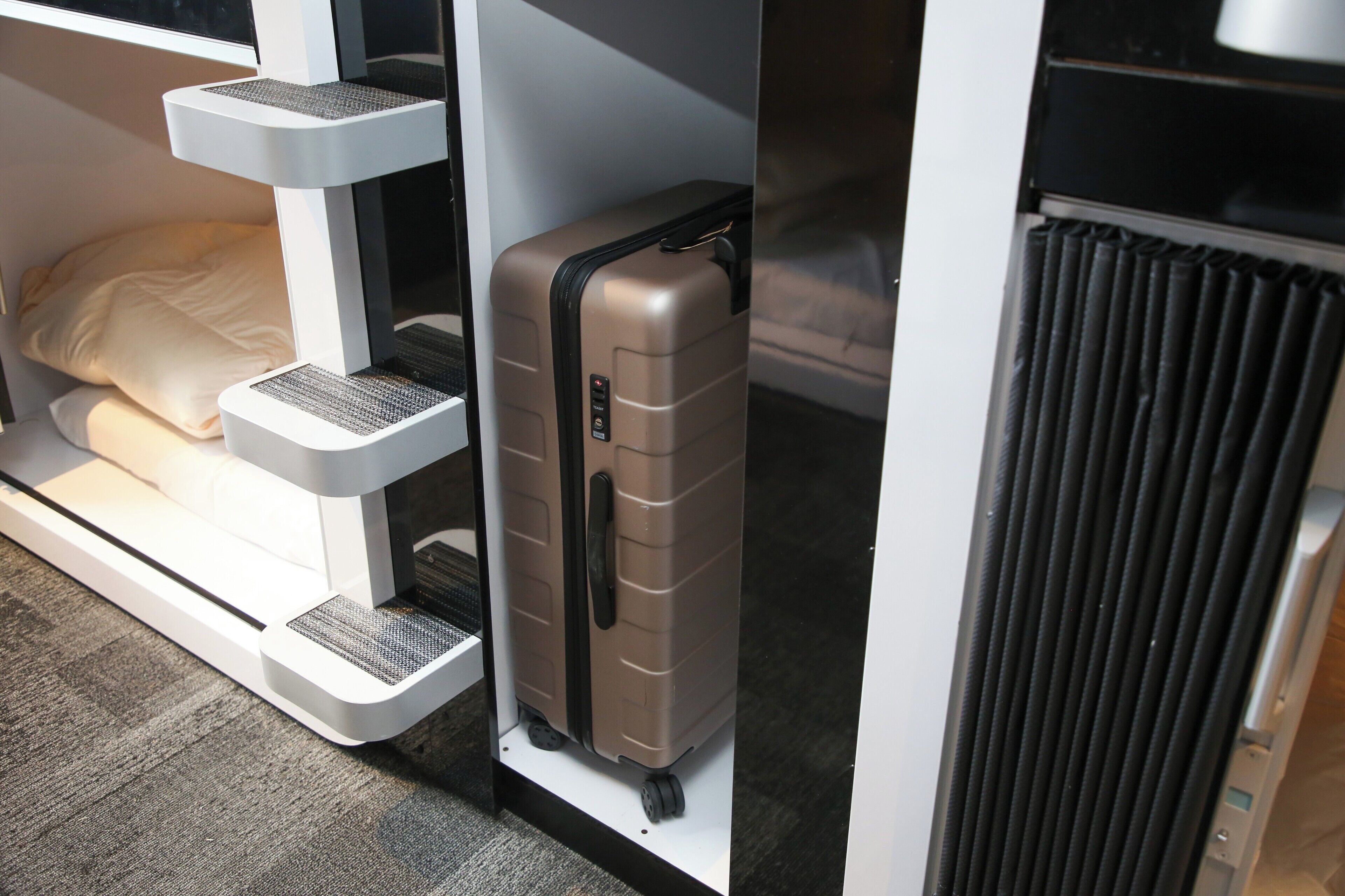 A compact room with a bed, a suitcase, and a radiator.
