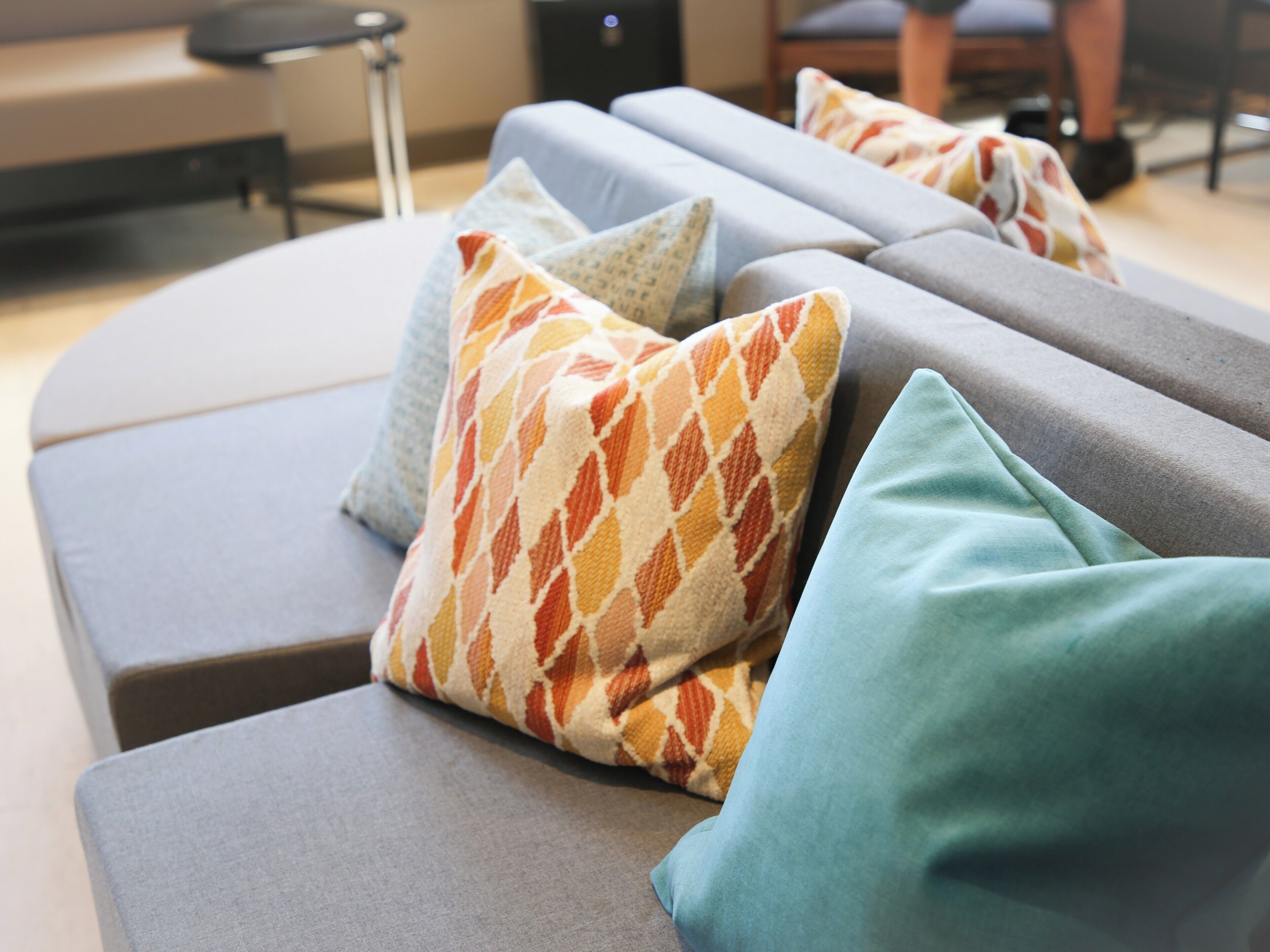 A modern lounge area with grey sofas and patterned throw pillows.