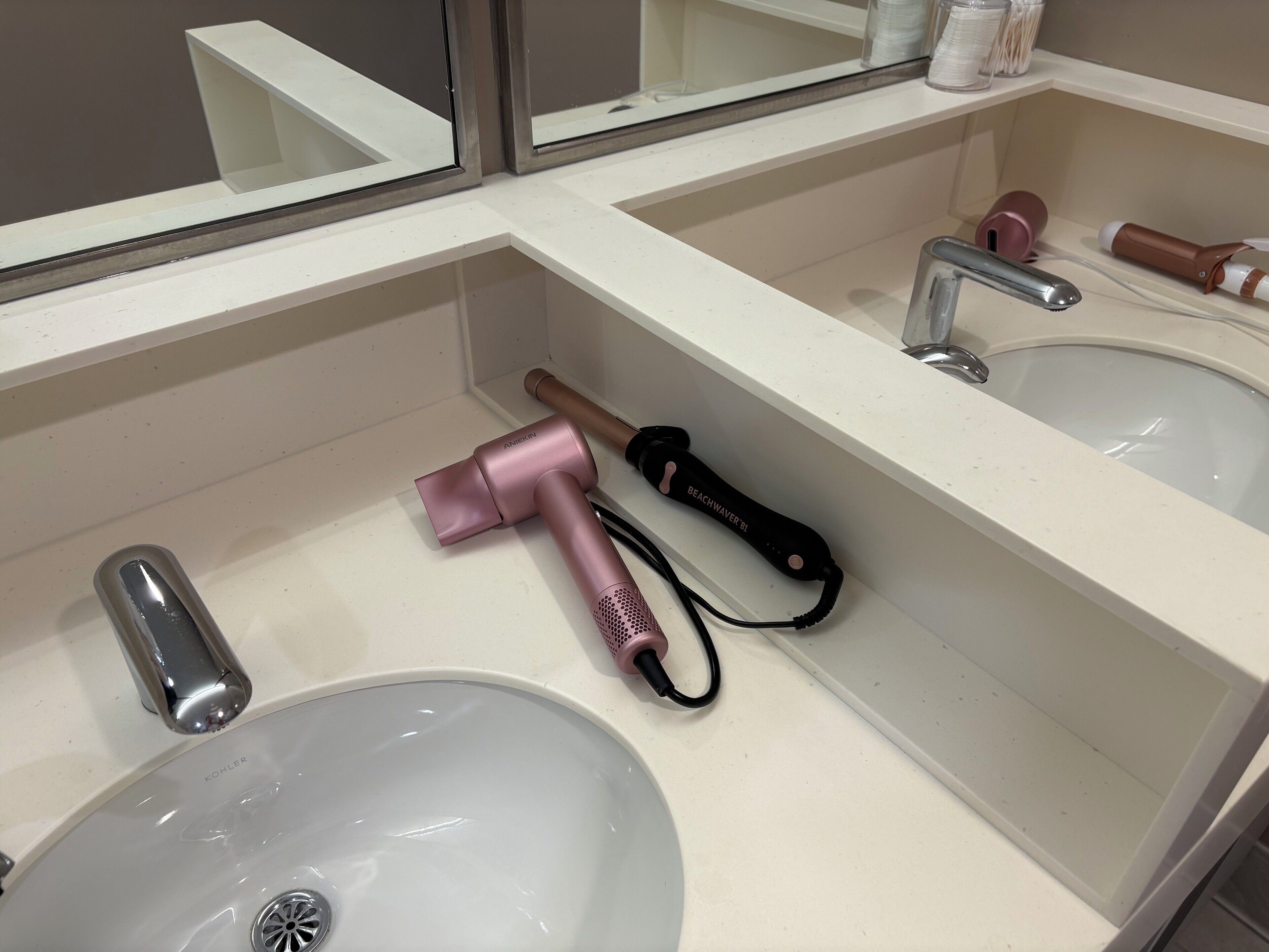 Un baño con dos lavabos, un espejo y un secador de pelo sobre el mostrador.