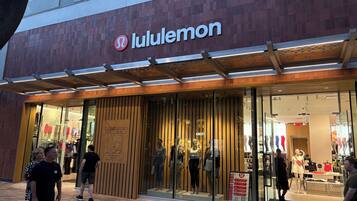 Una botiga Lululemon amb façana moderna, grans finestres de vidre i un disseny de panells de fusta.
