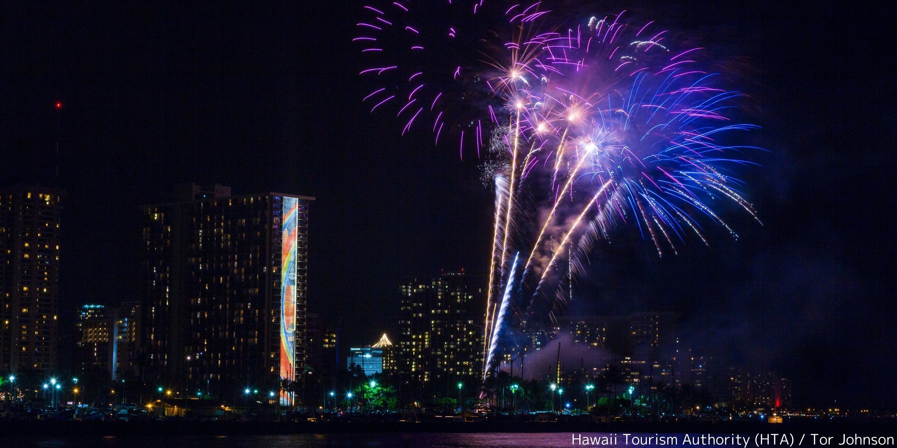 A nighttime cityscape with fireworks over a waterfront.