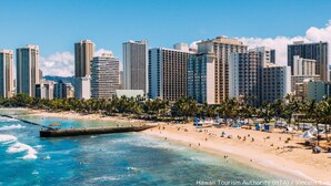 A beachfront hotel with a view of the ocean and city skyline.