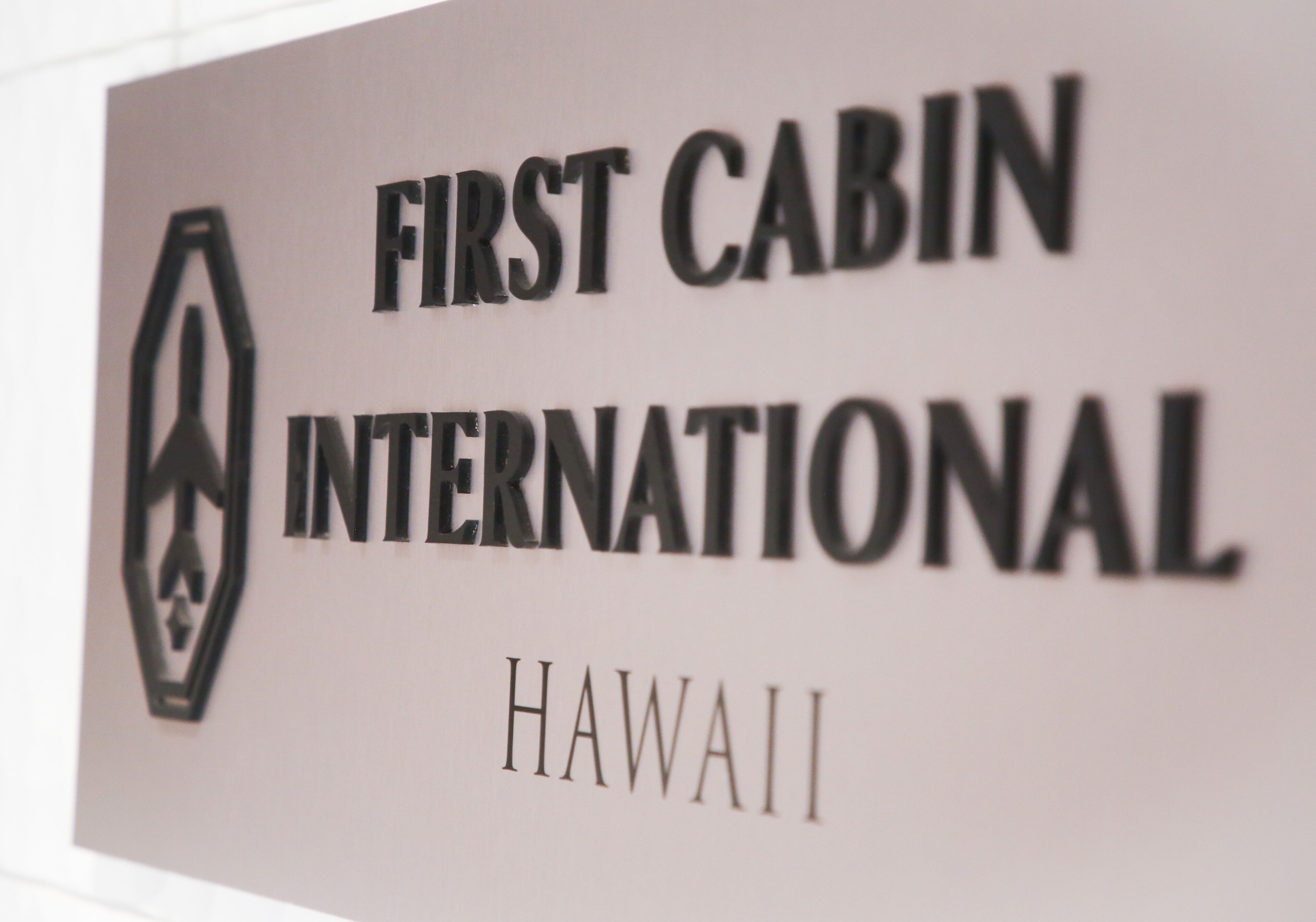 A sign for "First Cabin International" with a logo and the word "HAWAII" below it.