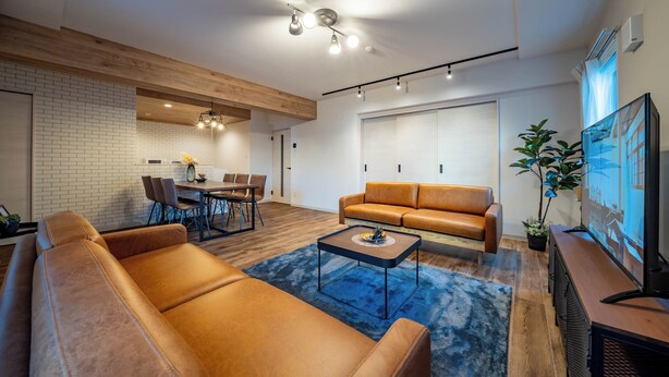 Una sala de estar moderna con un sofá de cuero marrón, una mesa de centro y un comedor con sillas y una mesa.