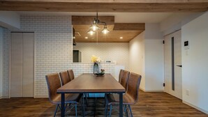 Un comedor moderno con una mesa de madera y sillas de cuero, una pared de ladrillo y un techo de madera.