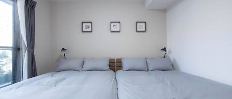 Un lit double avec une tête de lit en bois, deux tables de chevet et une fenêtre avec des rideaux.