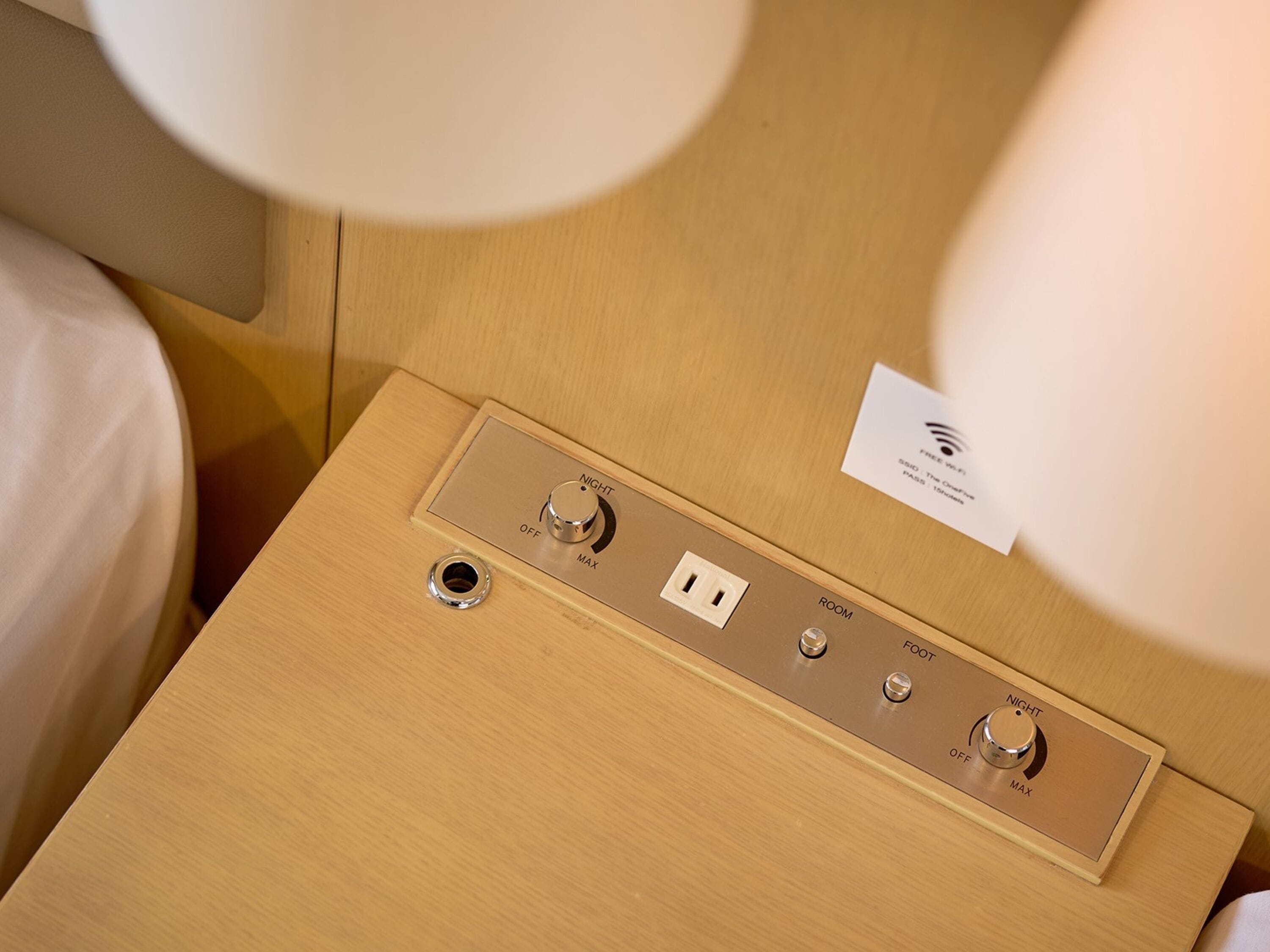 A wooden bedside table with a control panel featuring two knobs labeled NIGHT and MAX, and a power outlet.