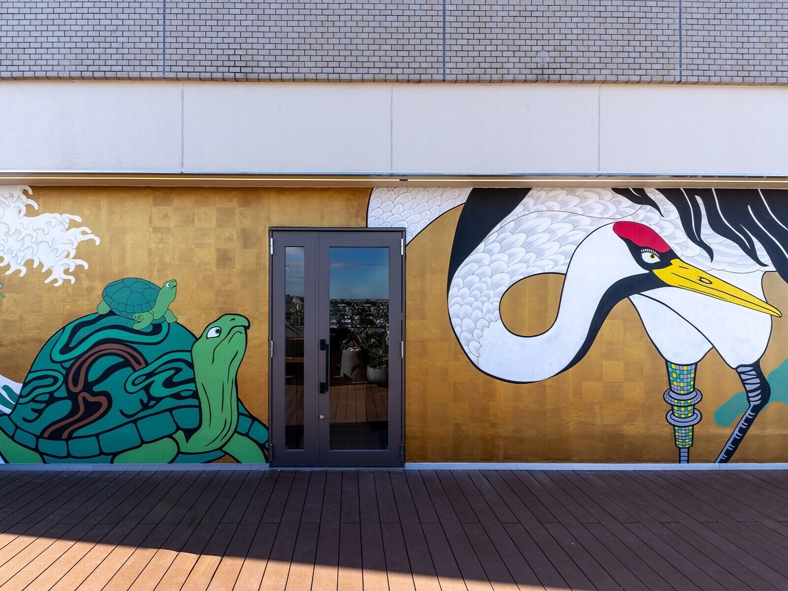 A building exterior with a mural of a turtle and a crane.