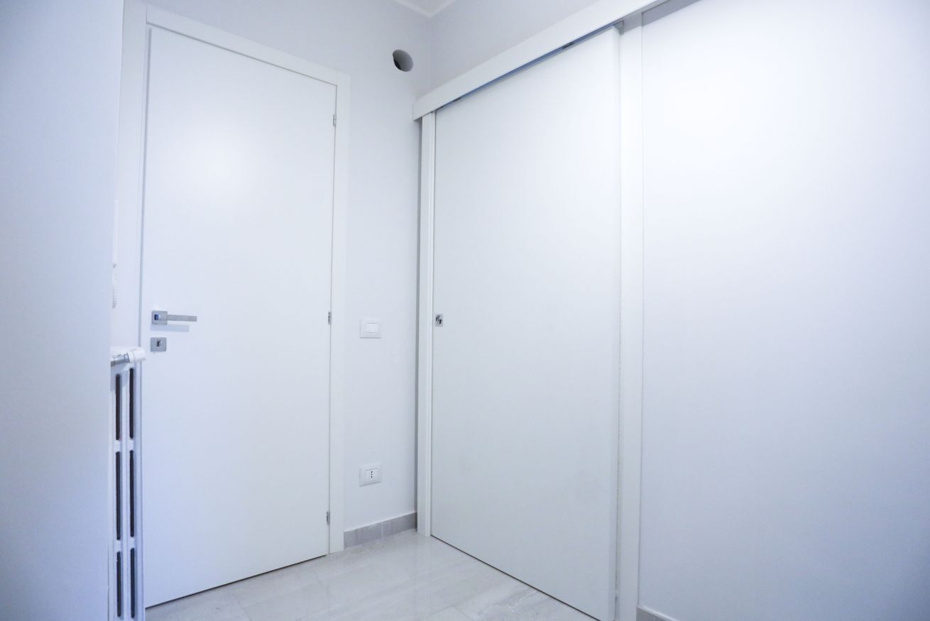 A white door with a handle, a radiator, and a light switch on the wall.