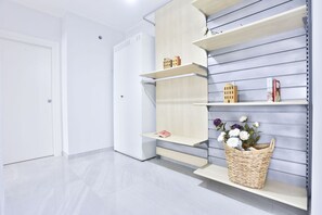 Ein Zimmer mit weißer Tür, einer eingebauten Regaleinheit mit einer Blumenkorb und einem weißen Kleiderschrank.