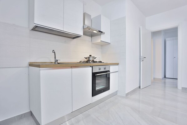 Una cocina moderna con gabinetes blancos, una campana extractora de acero inoxidable y un horno empotrado.