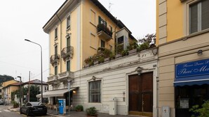 Vista de una calle con un edificio que tiene una puerta de madera grande, un balcón con plantas y el letrero de un restaurante tailandés.