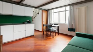 Una cocina moderna con armarios blancos, encimera verde y una zona de comedor con mesa y sillas.