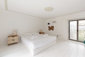 A bedroom with a bed, nightstands, a wall-mounted light, and a window with a decorative view. - GuestHost - Amendola- Cozy Apt on 2 Levels (Milano)