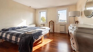 Een slaapkamer met een bed, dressoir, radiator en ramen.