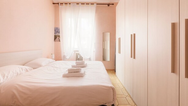 A bedroom with a bed, a bedside table, a mirror, and a wardrobe. - Cozy apartment located on the fourth floor of a typical Milanese building with lift. The accommodation is located not far from the M3 subway stop Maciachini, the new Isola Garibaldi district and the Niguarda district. The accommodation is equipped with a (Milano)