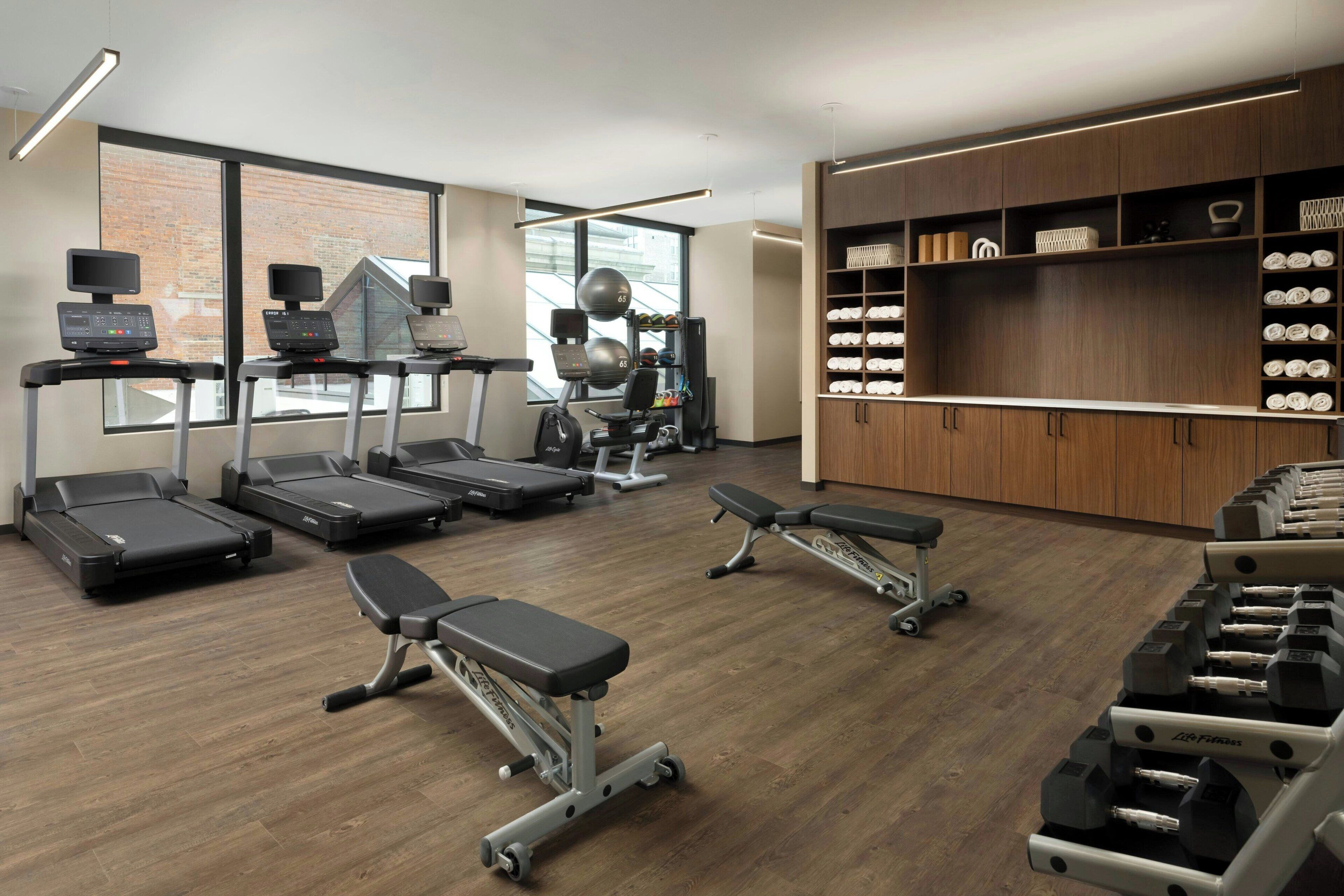 Une salle de sport équipée de tapis de course, de vélos elliptiques et de bancs de musculation.