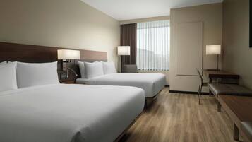 A hotel room with two beds, a desk, and a chair.