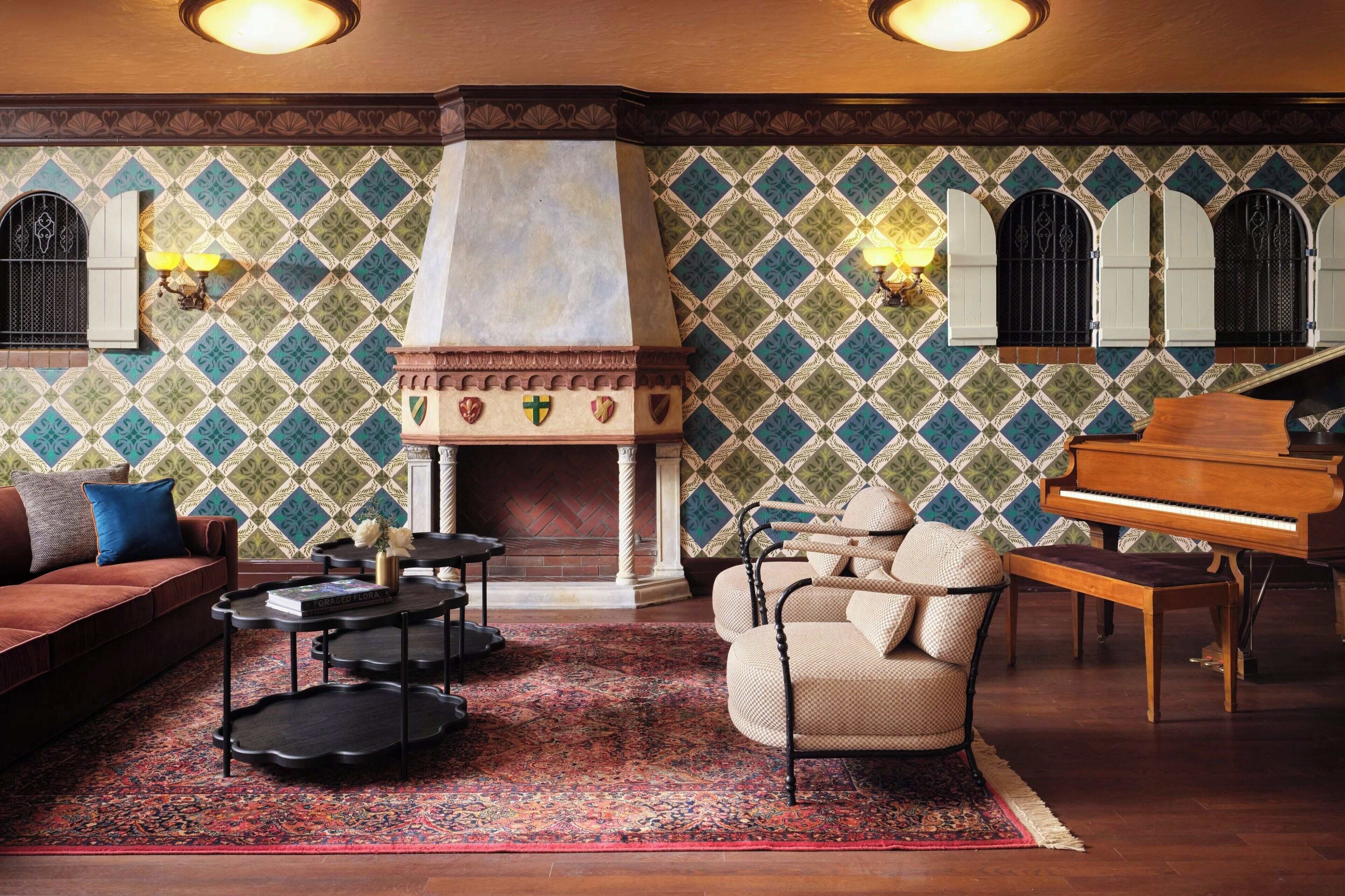 A cozy living room with a fireplace, a grand piano, and a patterned wall.