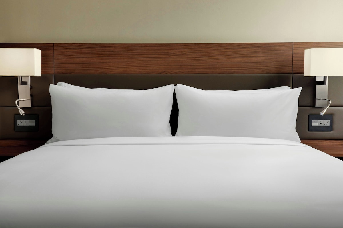 A hotel room with a large bed, two bedside tables with lamps, and a wooden headboard.